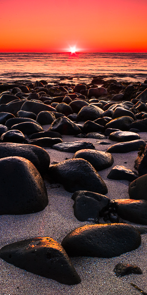 Rocks rest along the shores catching the last light of the day and enjoy the cleansing of ocean waters.  The summer sun of Iceland...