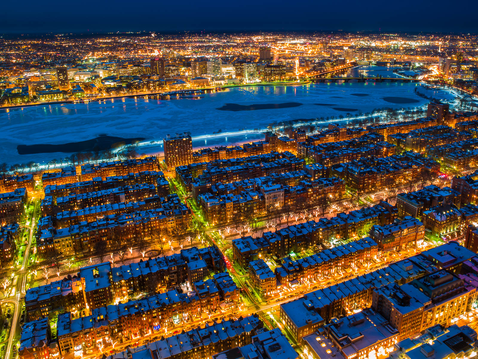 Snow capped brownstones and vibrant Christmas lights highlight the Charles River on this cold night.
