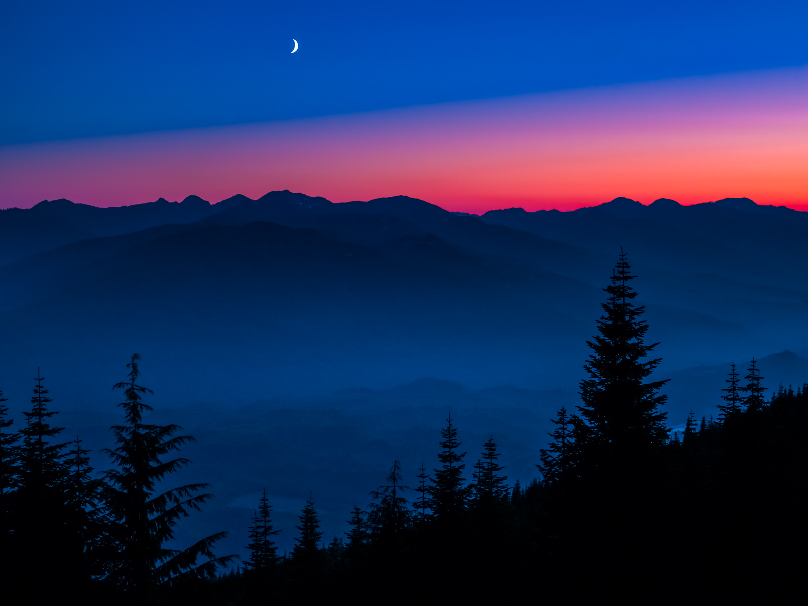 The crescent moon highlights the sky as the sunset turns to night.